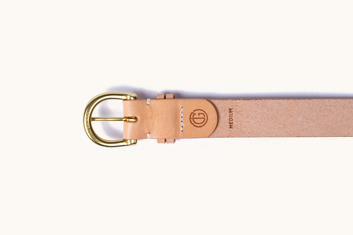 Natural tan leather belt with a brass D-ring buckle engraved 'BRASS', a debossed logo, and 'MEDIUM' text.