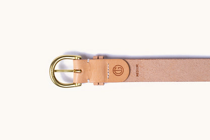 Natural tan leather belt with a brass D-ring buckle engraved 'BRASS', a debossed logo, and 'MEDIUM' text.