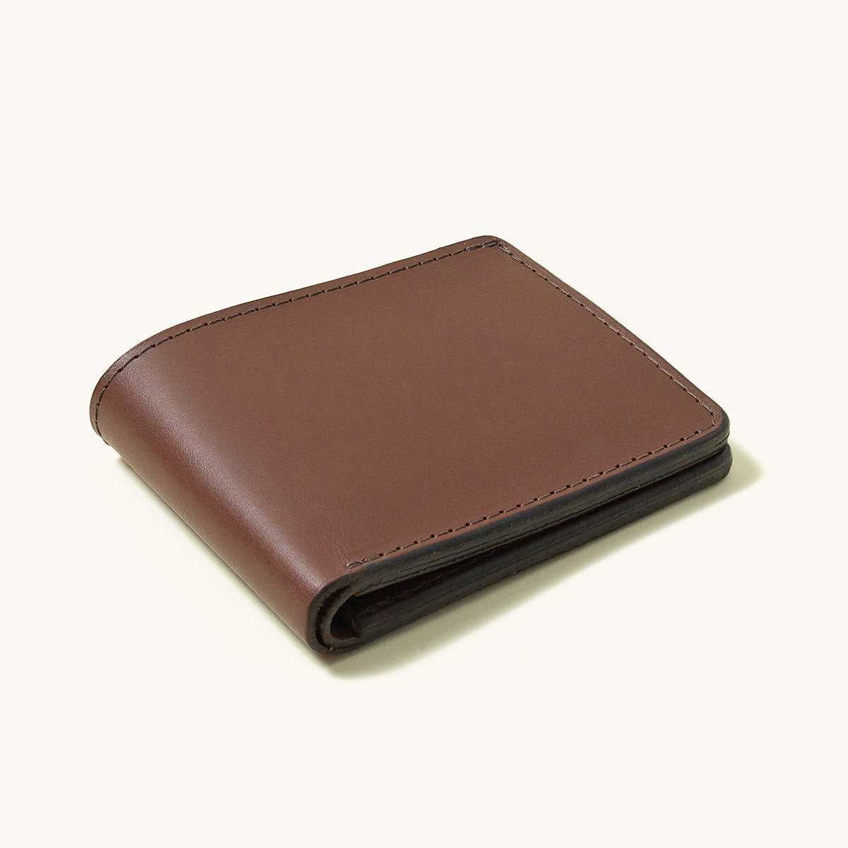 Cognac leather bifold wallet with dark stitching, viewed at an angle.