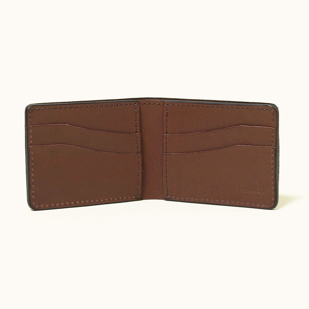 Cognac leather bifold wallet by Tanner Goods, open to show six card slots and an embossed logo.