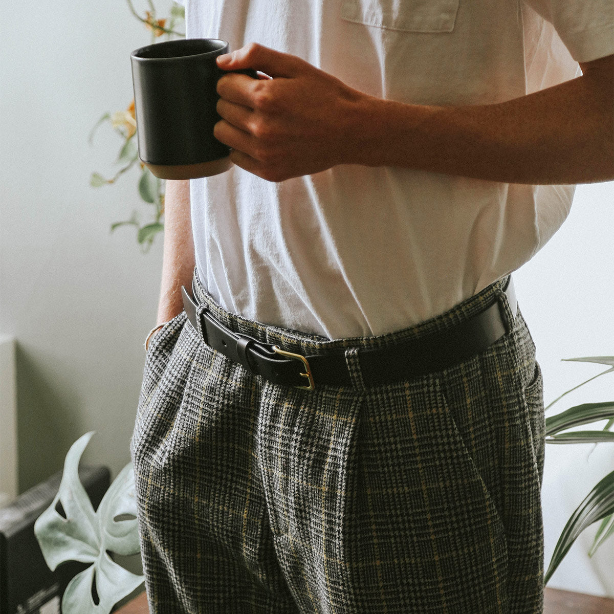 Black Daily Belt with a gold buckle, styled with pleated plaid pants and a white t-shirt.
