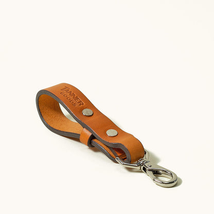 Saddle tan leather key lanyard by Tanner Goods, with silver-toned hardware and an embossed logo.