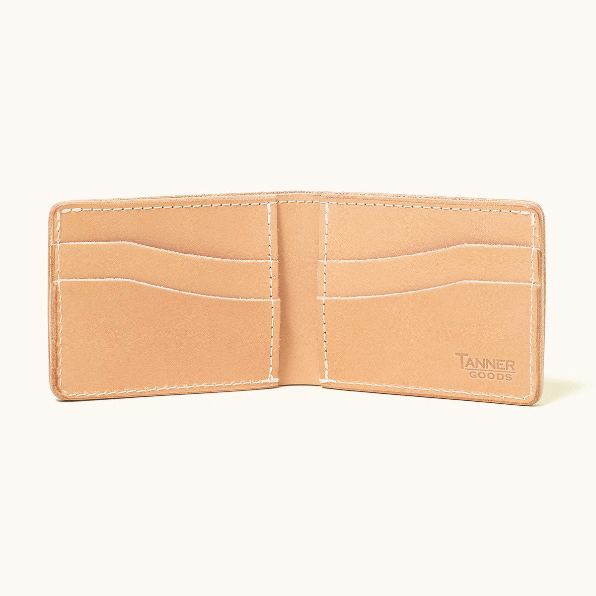 Natural leather utility bifold wallet by Tanner Goods, open to show card slots and white stitching.