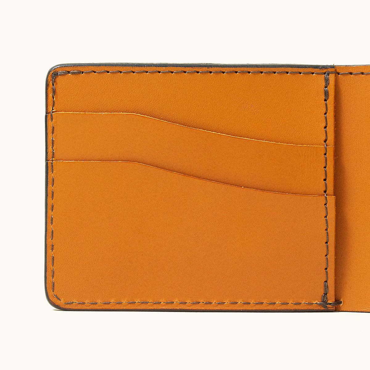 Saddle Tan Utility Bifold wallet interior with three leather card slots and visible stitching.