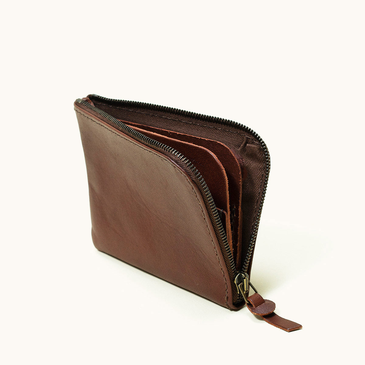 Cognac leather Universal Zip Wallet, slightly open showing zipper and internal compartments.
