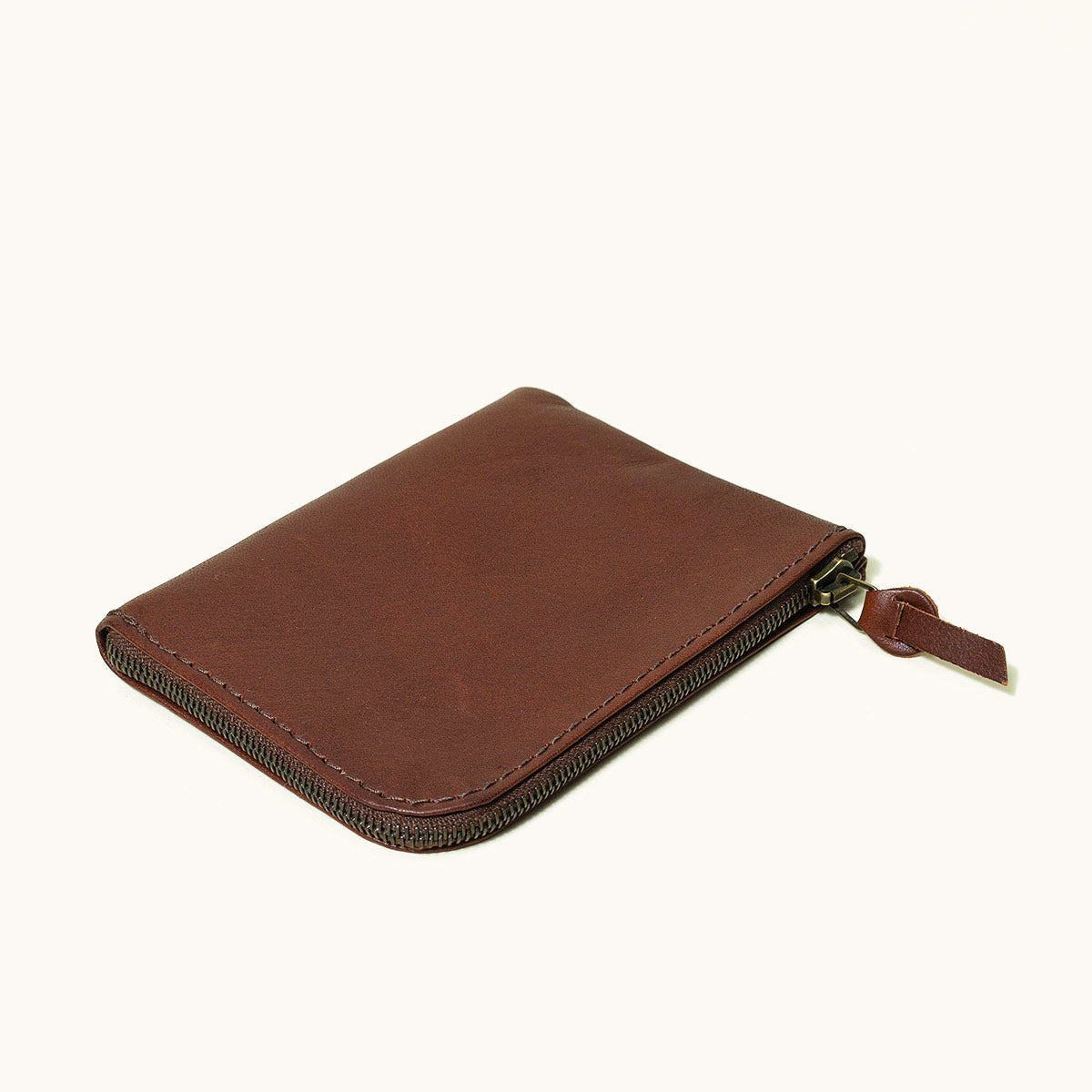 Closed cognac leather universal zip wallet with a brown zipper and leather pull tab.
