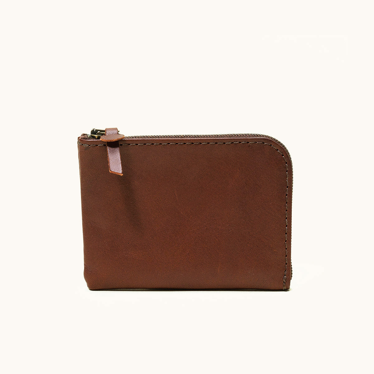 Cognac leather zip wallet with exposed stitching and a leather tab zipper pull, shown from the front.