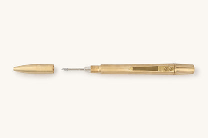 Brass mechanical pen by Memori Mechanico, lying horizontally with its cap removed, revealing the silver pen tip and pocket clip.