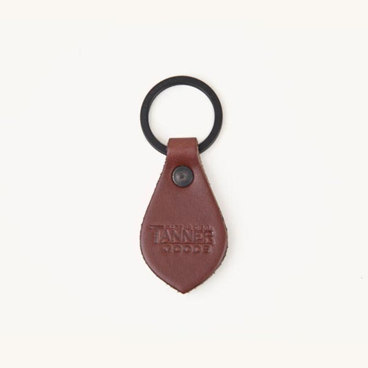 Cognac leather Key Fob with a teardrop shape, black metal ring, and embossed text "TANNER GOODS".