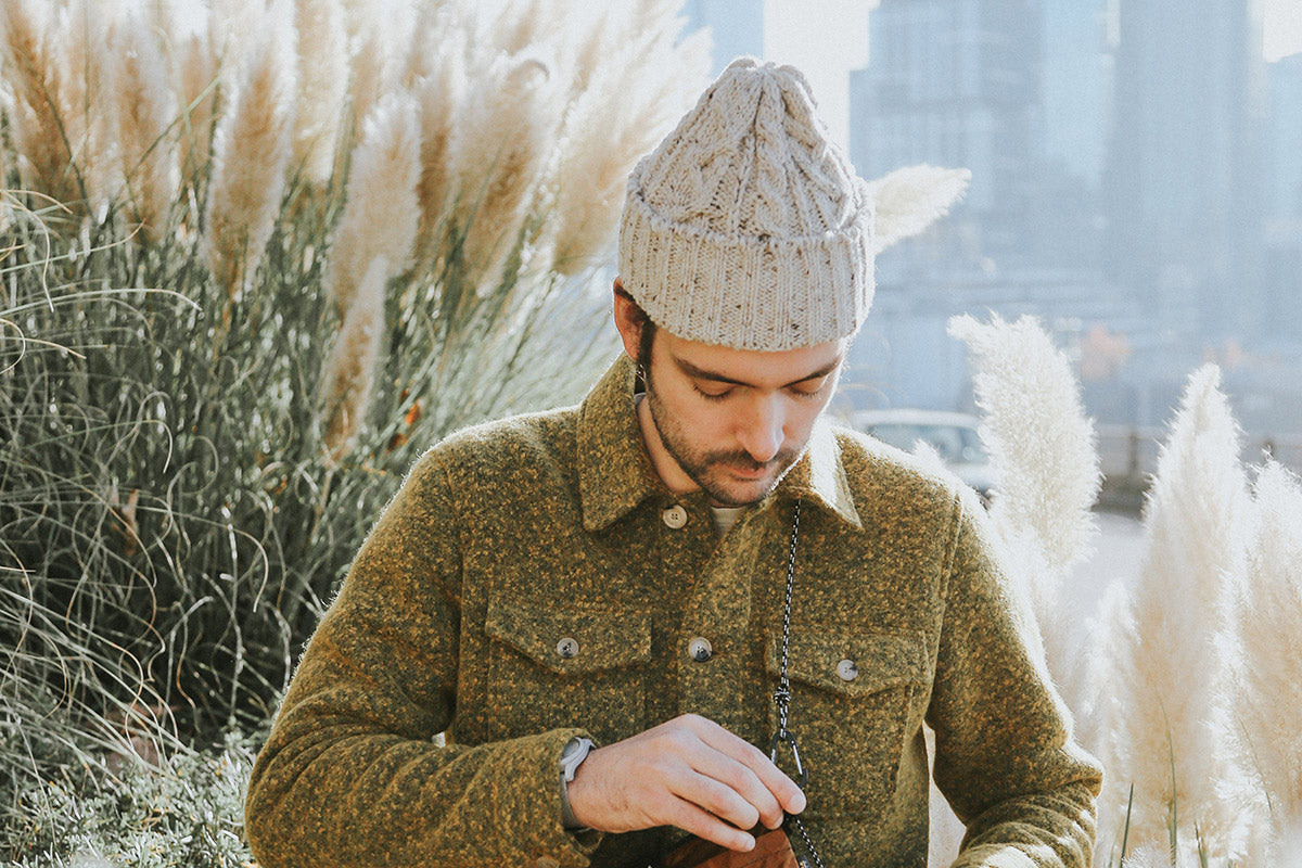 Light beige speckled cable knit cap worn by a man with an olive green textured jacket.