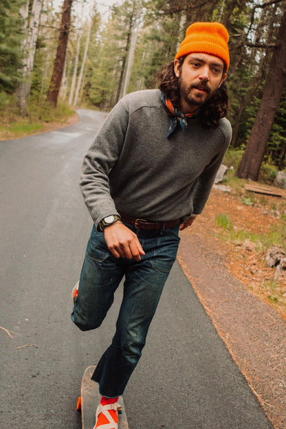 Cognac classic leather belt with a simple buckle, worn by a man in dark blue jeans.