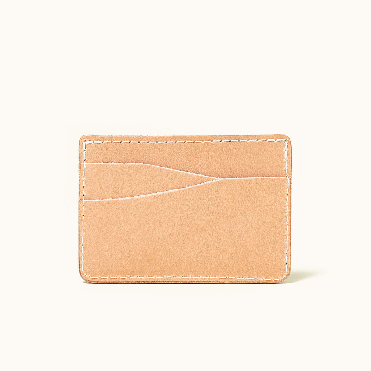 Natural leather wallet with two curved card slots and white stitching, shown front view.