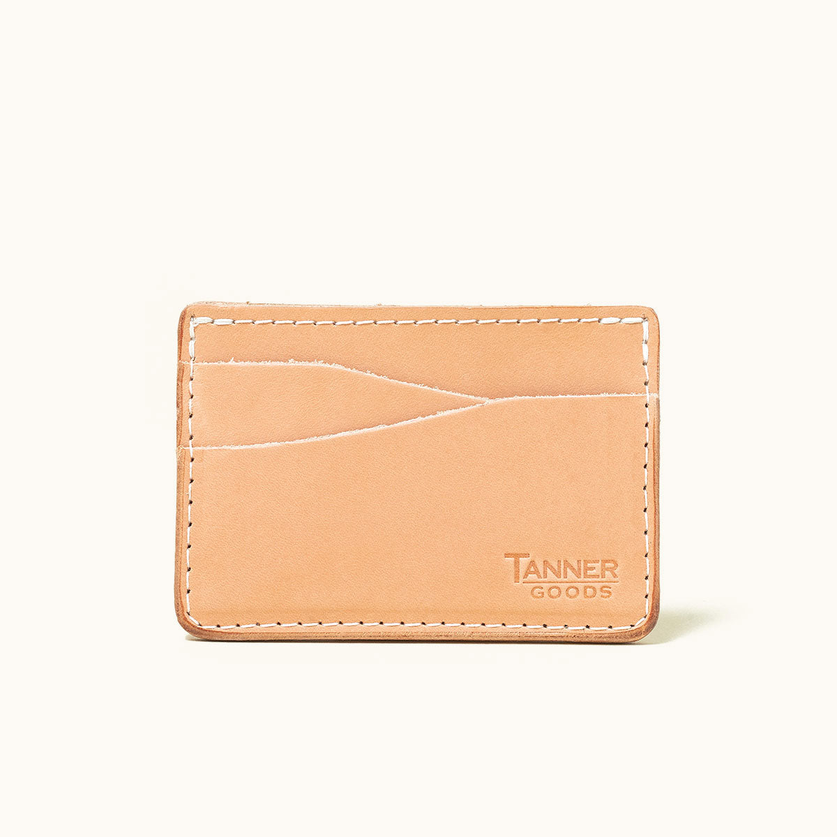Natural leather wallet by Tanner Goods, featuring wavy card slots, light stitching, and a debossed logo.