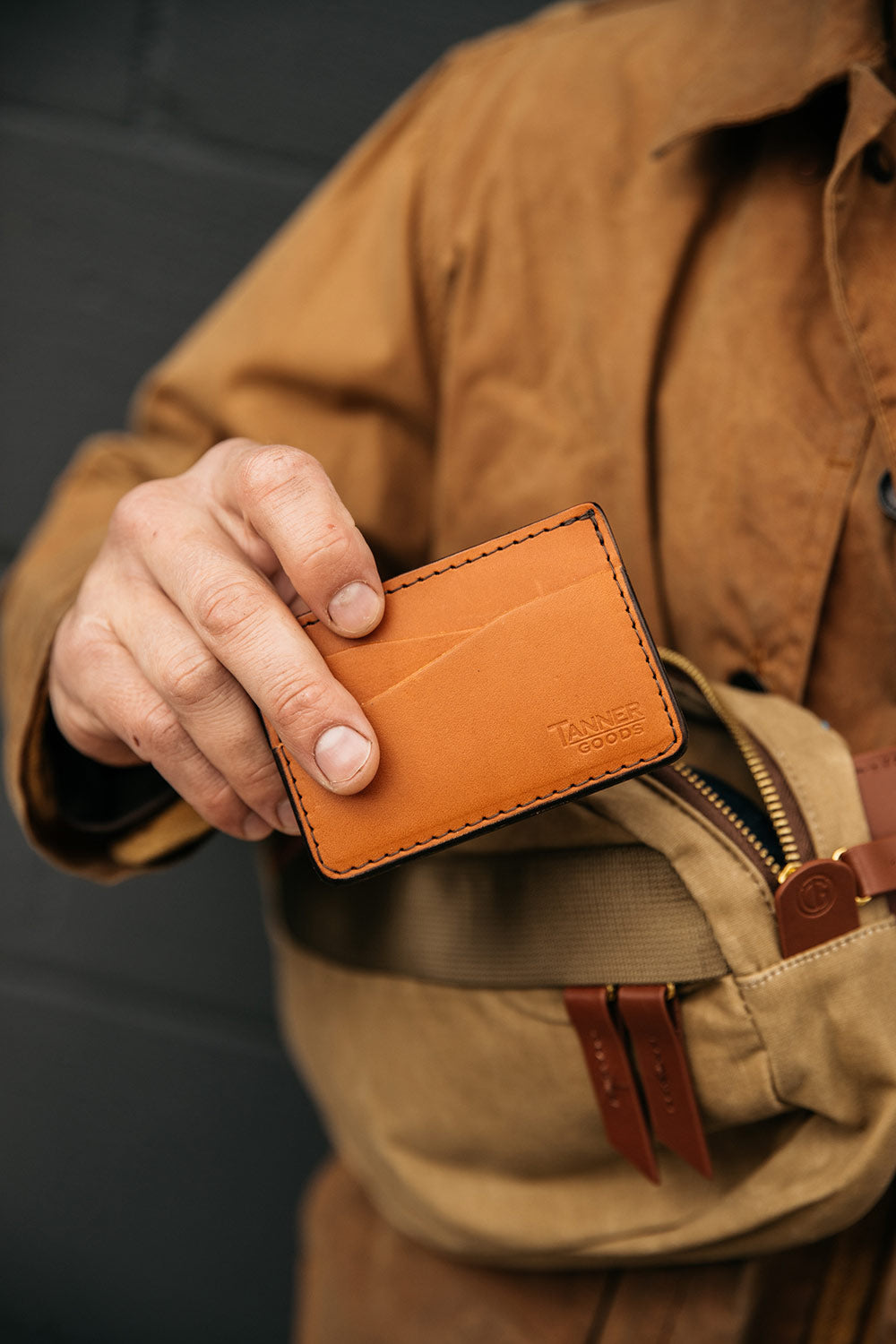 Saddle tan leather wallet by Tanner Goods, with visible card slots and black stitching, held in a hand.