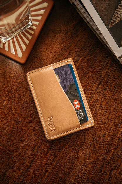 Natural leather minimalist wallet by Tanner Goods, with an HSBC Premier card visible, on a wooden table.