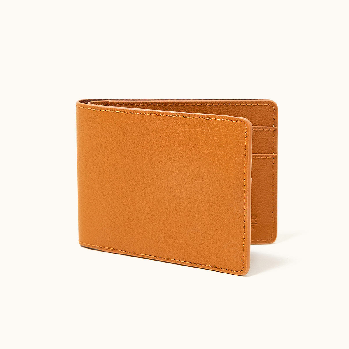Saddle tan recycled leather utility bifold, partially open, revealing card slots and fine grain texture.