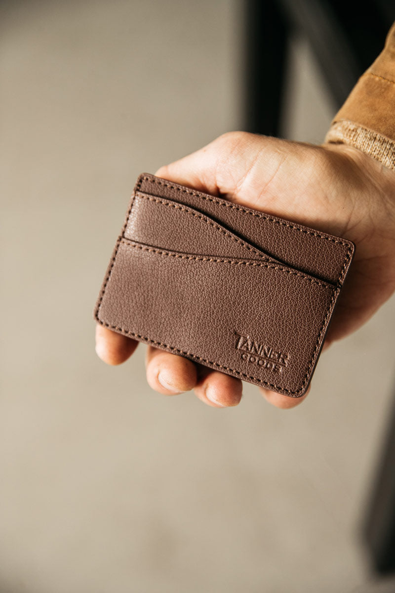 Slim cognac recycled leather card holder by Tanner Goods with pebbled texture, multiple card slots, held in a person's hand.