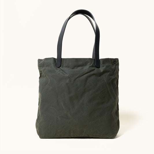 Juniper green waxed canvas tote bag with black leather handles and subtle fabric wrinkles, front view.