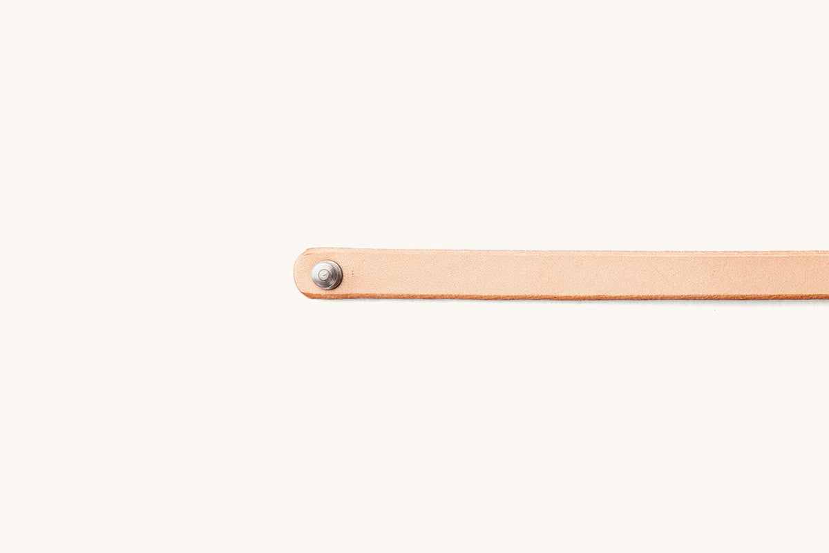 Natural leather double wrap wristband with a silver rivet on the rounded end.