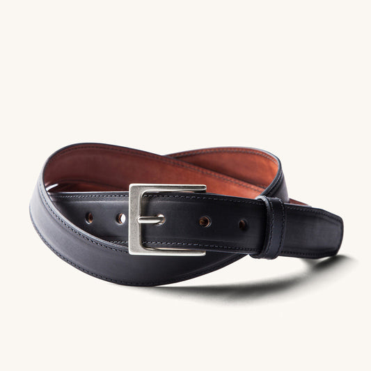 Black dress belt with a silver rectangular buckle, brown lining, and visible stitching, displayed coiled.