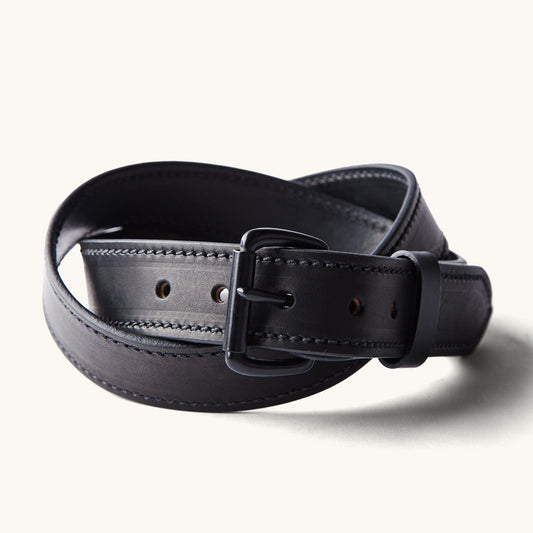 Black Heritage Belt coiled, featuring a matte black buckle, belt loop, and prominent stitching.