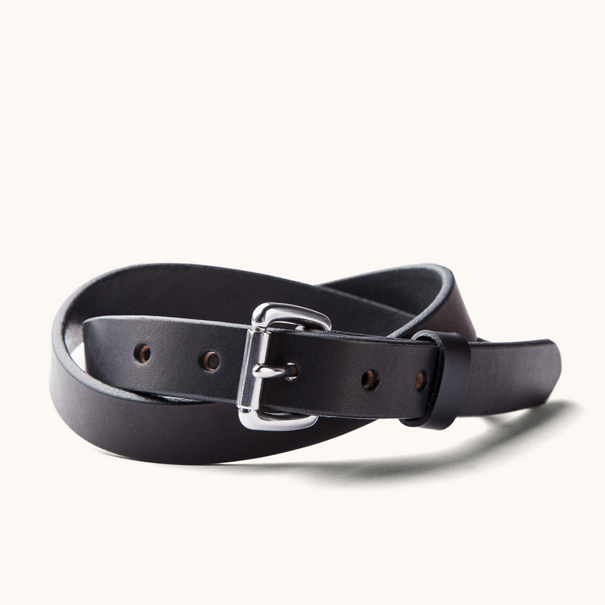 Black skinny standard belt made of smooth leather, with a polished silver buckle, coiled to show punched holes.