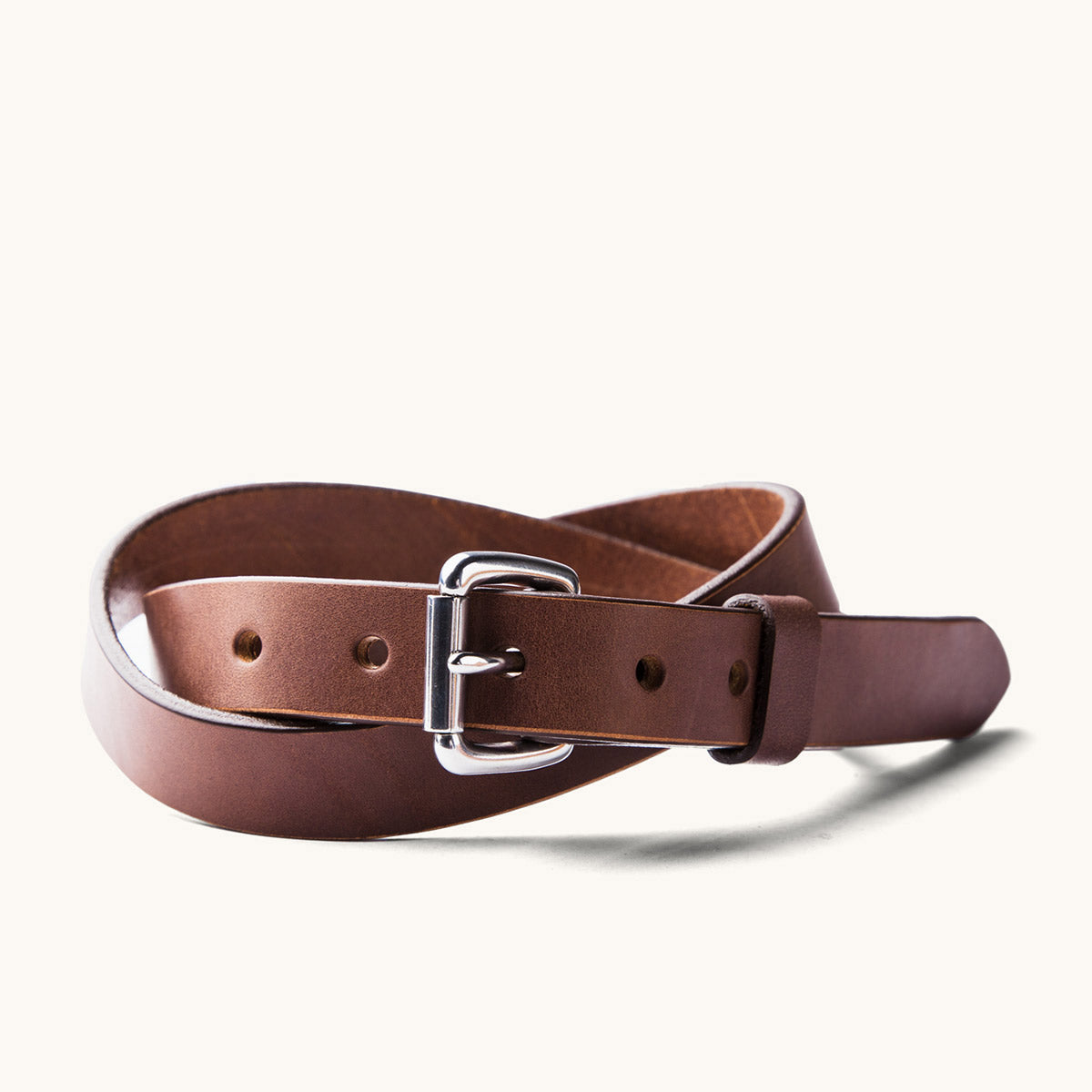 Cognac leather skinny standard belt with a silver-tone buckle, coiled.