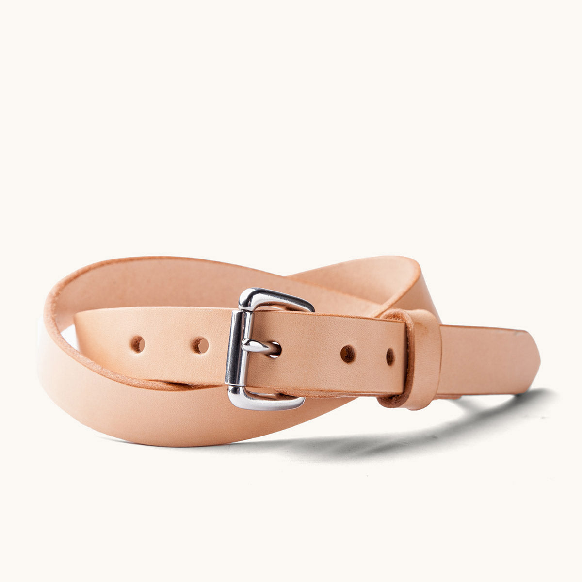 Natural skinny leather belt with a silver-toned buckle, loosely coiled on a white background.