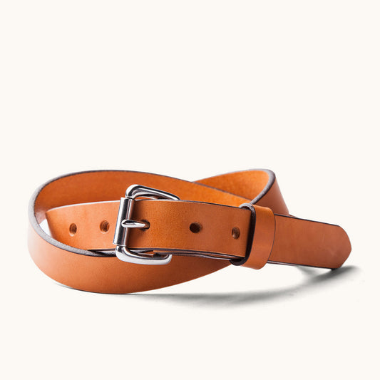 Skinny Standard Belt in saddle tan leather with a silver buckle, coiled.