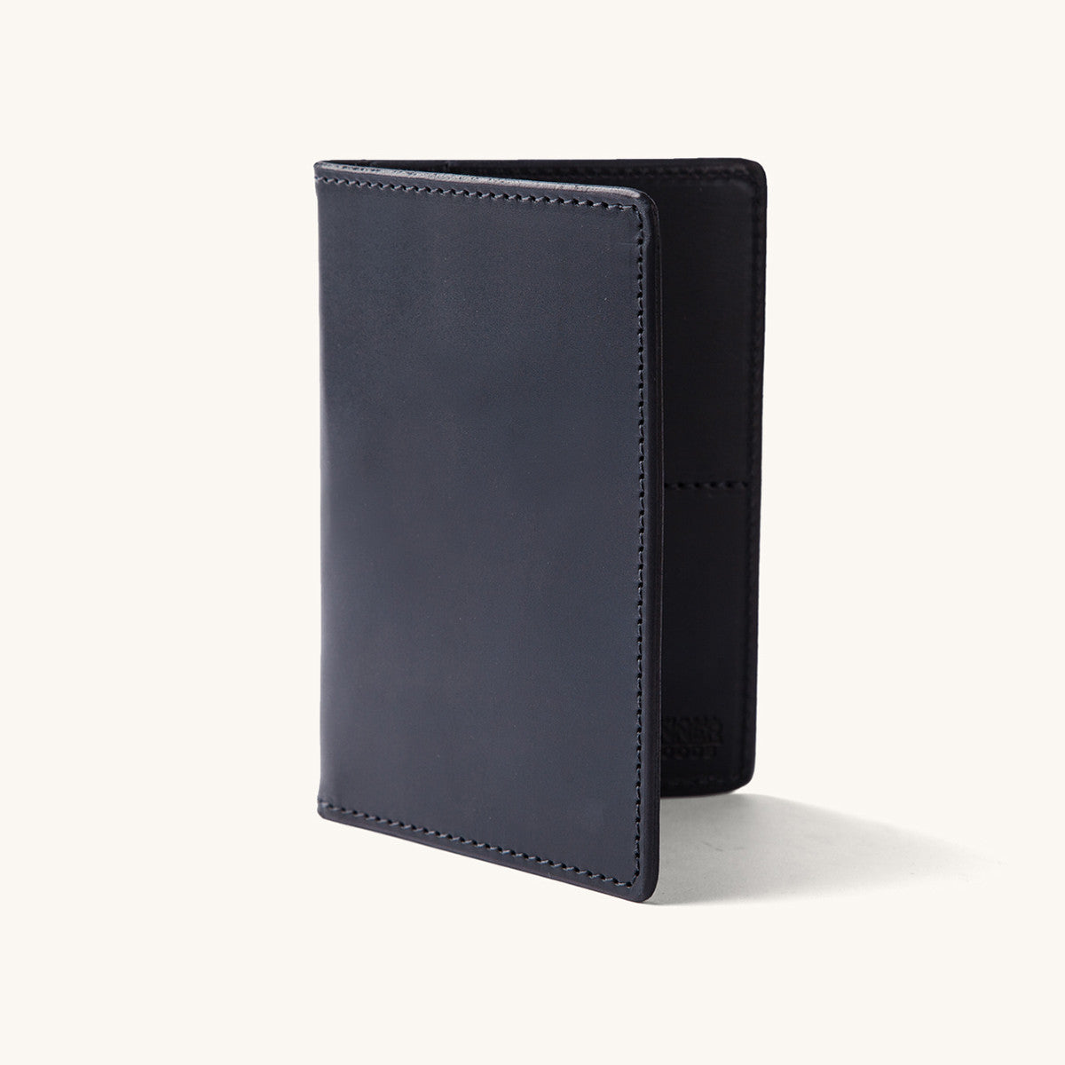 Black leather travel wallet standing upright, slightly open, featuring a smooth finish and visible stitching.