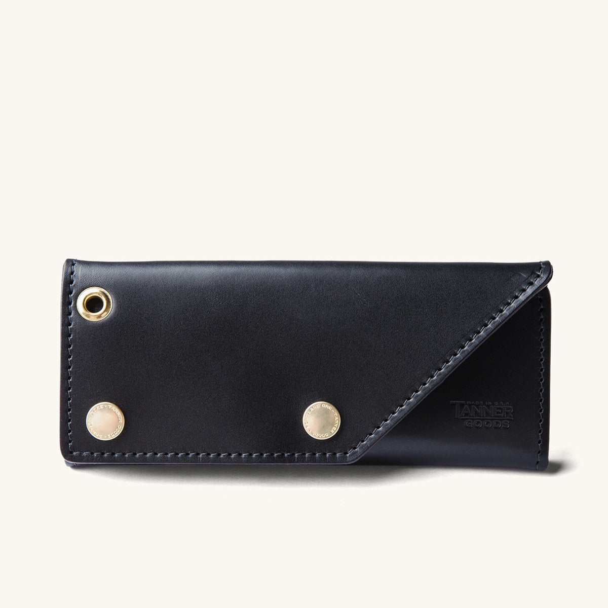 Black leather Workman Wallet by Tanner Goods with a gold-toned grommet and two brass snap buttons.
